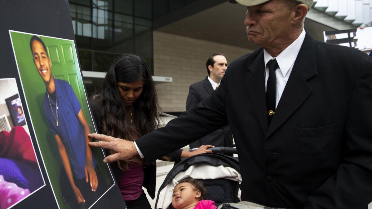 John Weber touches a photo of his son, Anthony Weber, 16, who was killed by an L.A. County sheriff's deputy in 2018. Anthony's family has said they want all the money from a legal settlement to go to his young daughter, Violet, in the stroller.