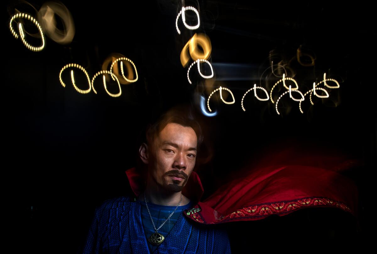 Man in red cape in dark theater with artistic lighting
