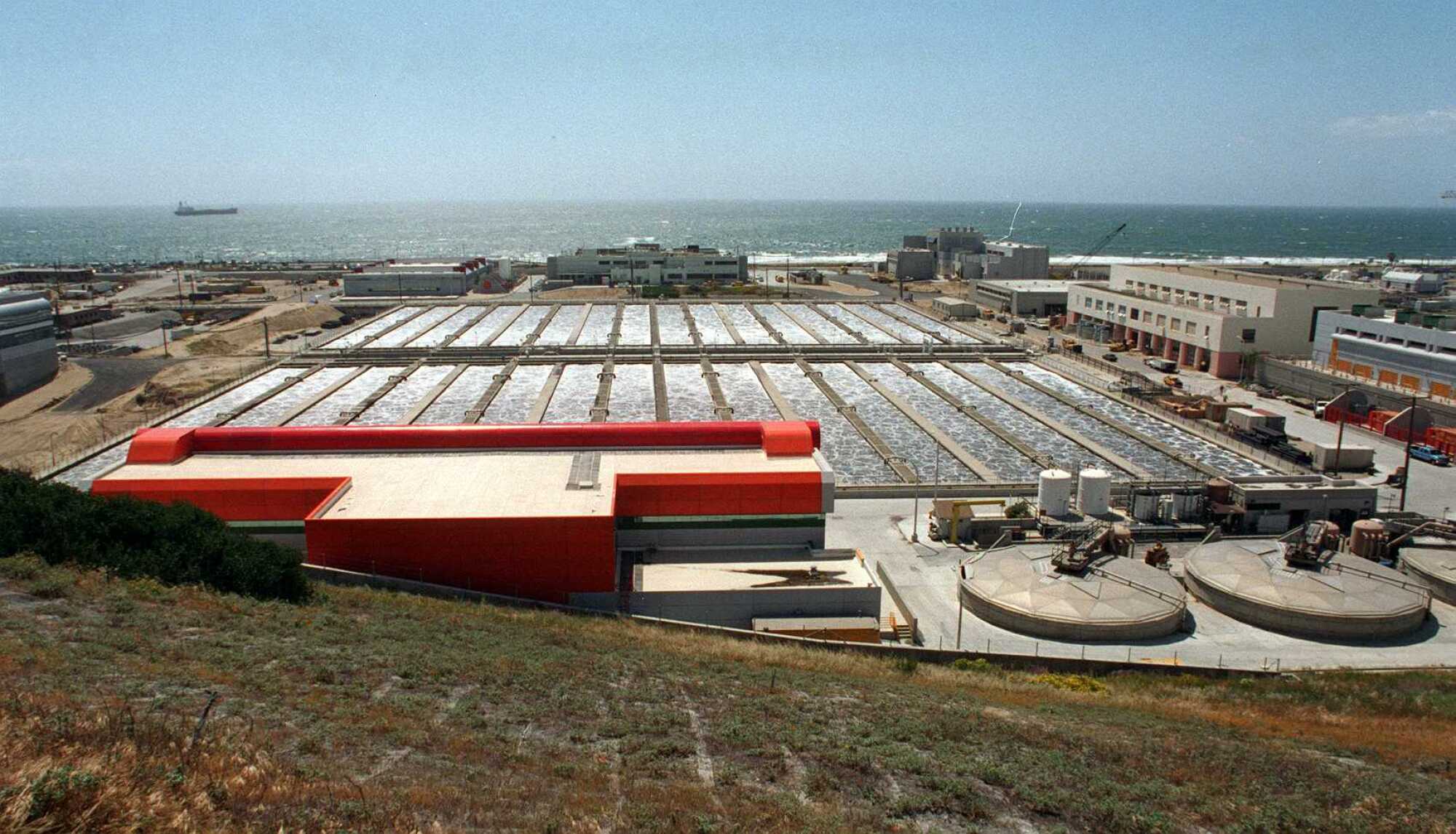 Covered water treatment tanks with the ocean in the distance