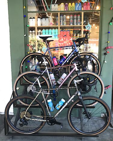 Three bikes lined up in a rack outside a store's window