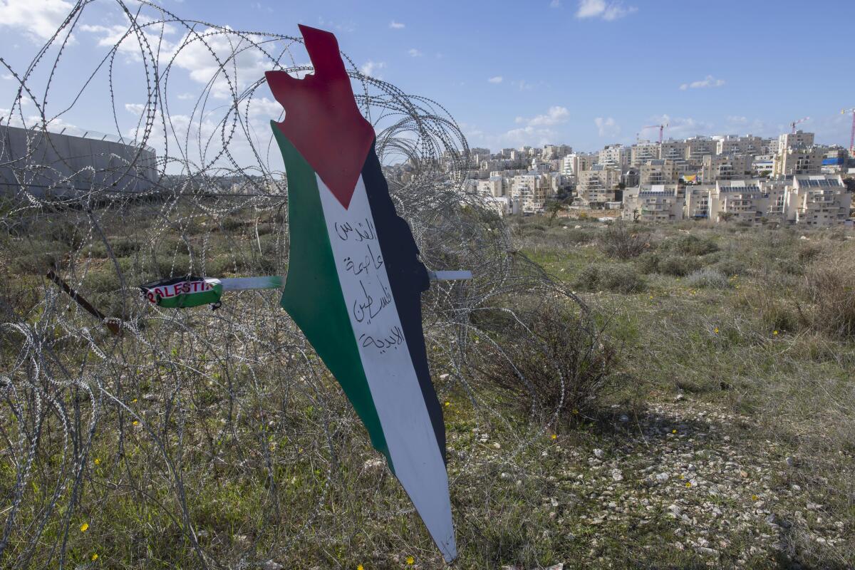 A placard shaped like a map of Israel and painted with the colors of the Palestinian flag and Arabic script.