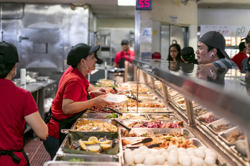 A member of the staff helps a customer at the turo turo hot-food counter at Arko Foods International.