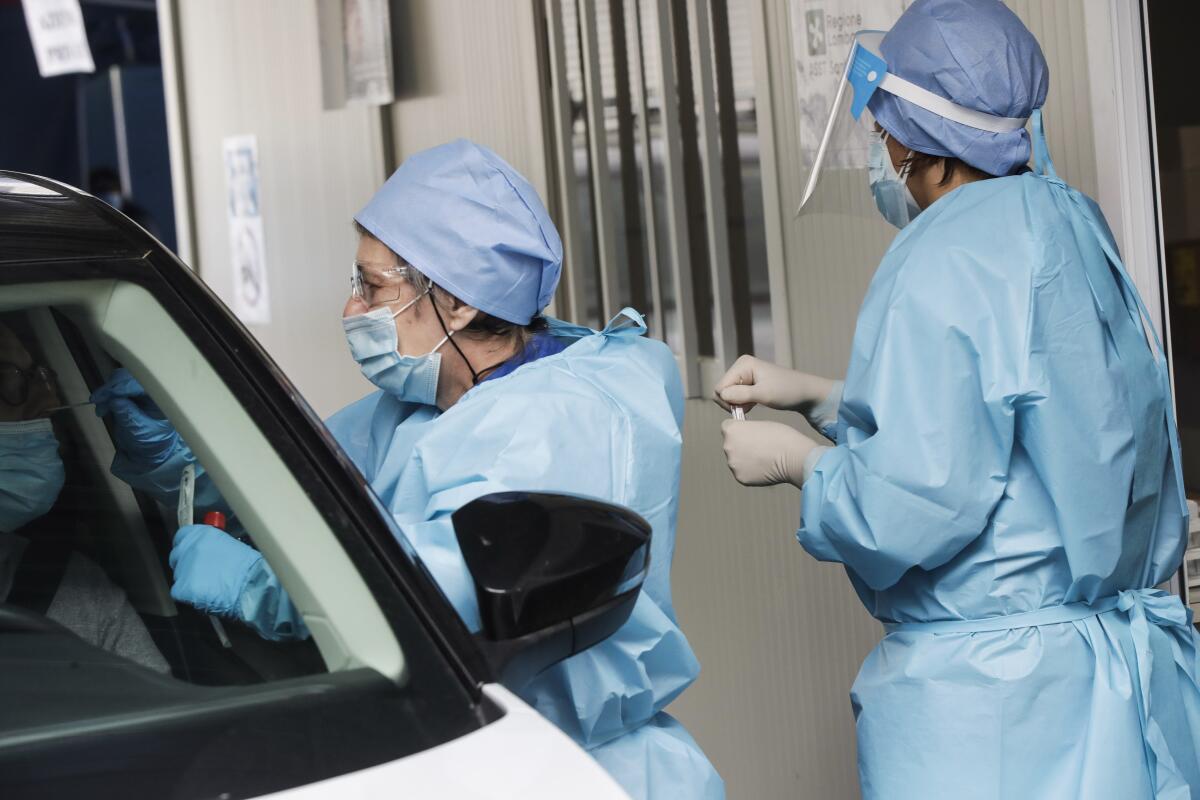Medical workers collect test samples from a person in a car in Milan, Italy. 