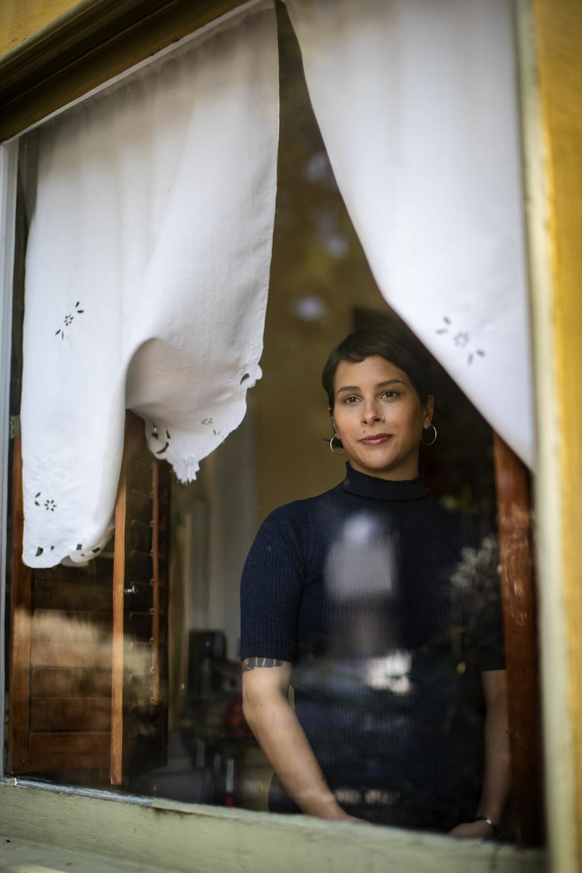 Tongva poet Megan Dorame looks through a window.  