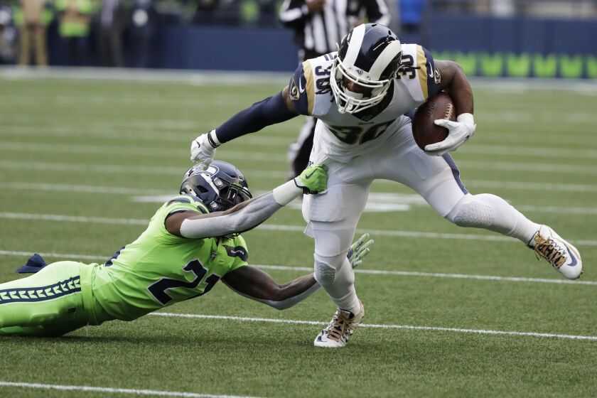 Los Angeles Rams running back Todd Gurley, right, tries to fend off Seattle Seahawks cornerback Tre Flowers (21) during the first half of an NFL football game, Thursday, Oct. 3, 2019, in Seattle. (AP Photo/Elaine Thompson)