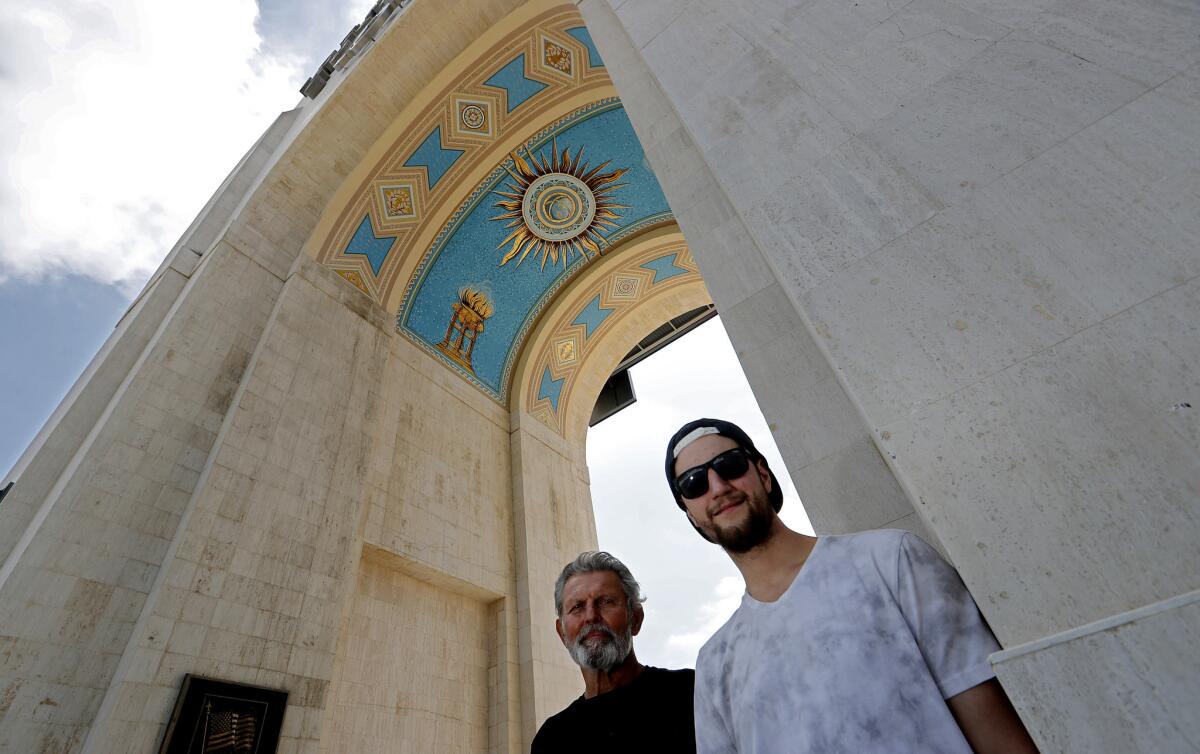 Nick Rosien, at right with his uncle Mick Rosien, visits the L.A. Coliseum mural that his father helped to create.