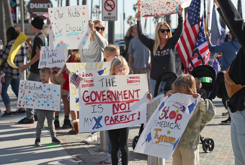 Kids of supporters hold signs during Children's Medical Freedom rally at the Huntington Beach Pier Plaza on Monday.
