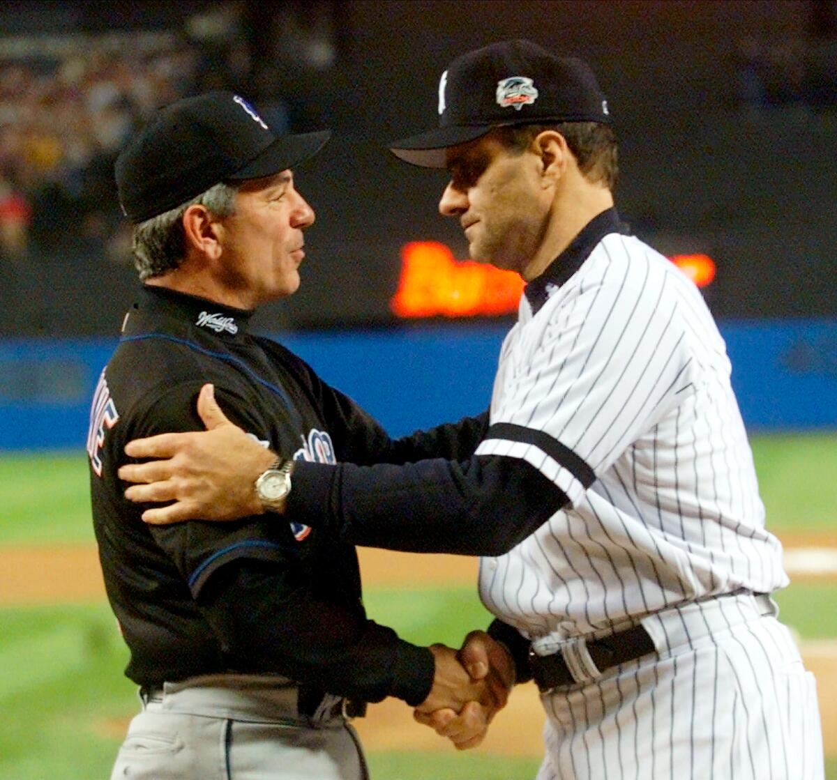 FILE - In this Oct. 21, 2000, file photo, New York Yankees manager Joe Torre, right, greets New York Mets manager Bobby Valentine before the start of Game 1 of baseball's World Series at Yankee Stadium in New York. Sports teams will hold ceremonies Saturday, Sept. 11, 2021, to mark the 20th anniversary of the Sept. 11 terrorist attacks. Valentine, manager of the 2001 Mets, will throw a ceremonial first pitch to Torre, manager of the 2001 Yankees. (AP Photo/Mark Lennihan, Pool, File)