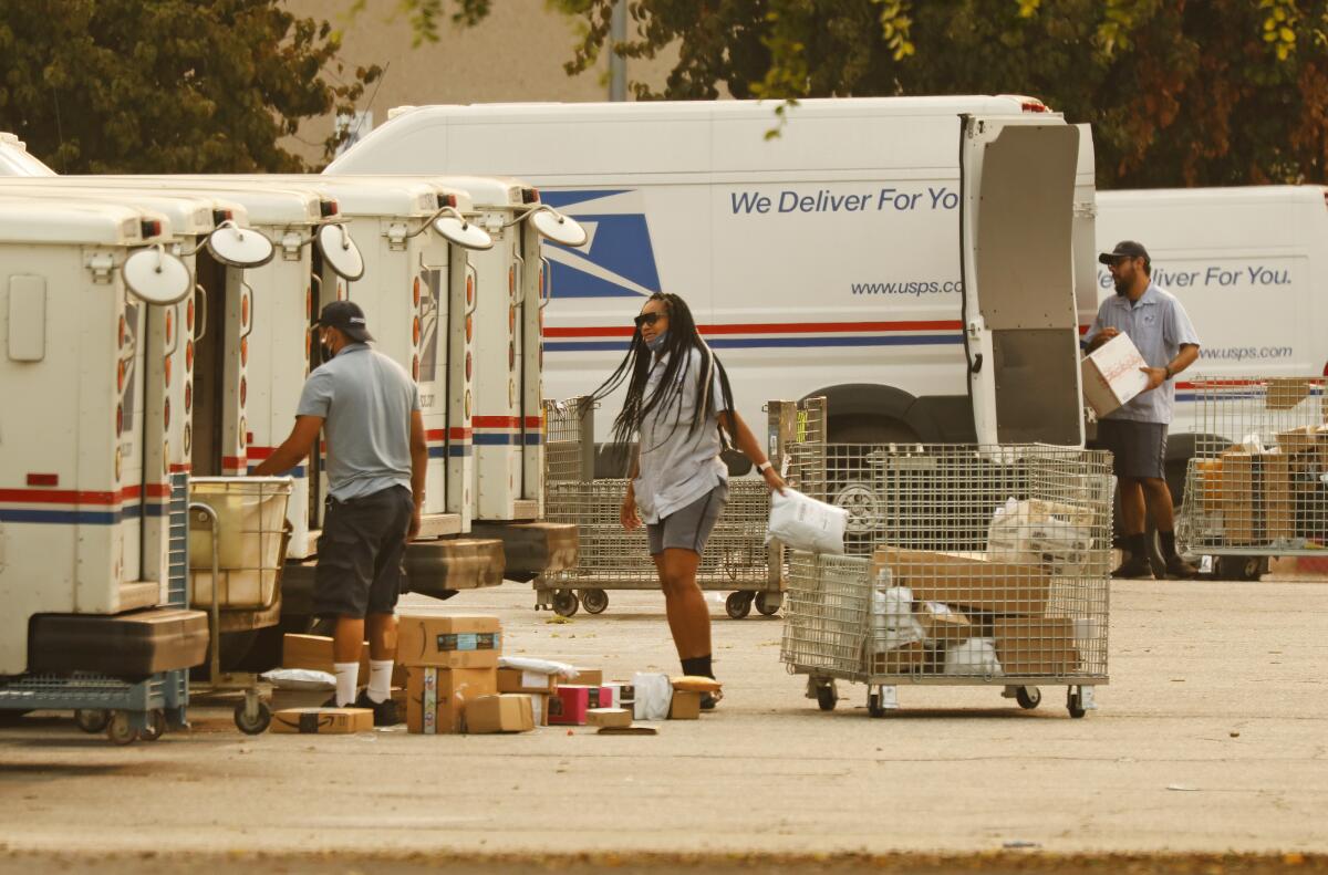 People with carts loading mail trucks.