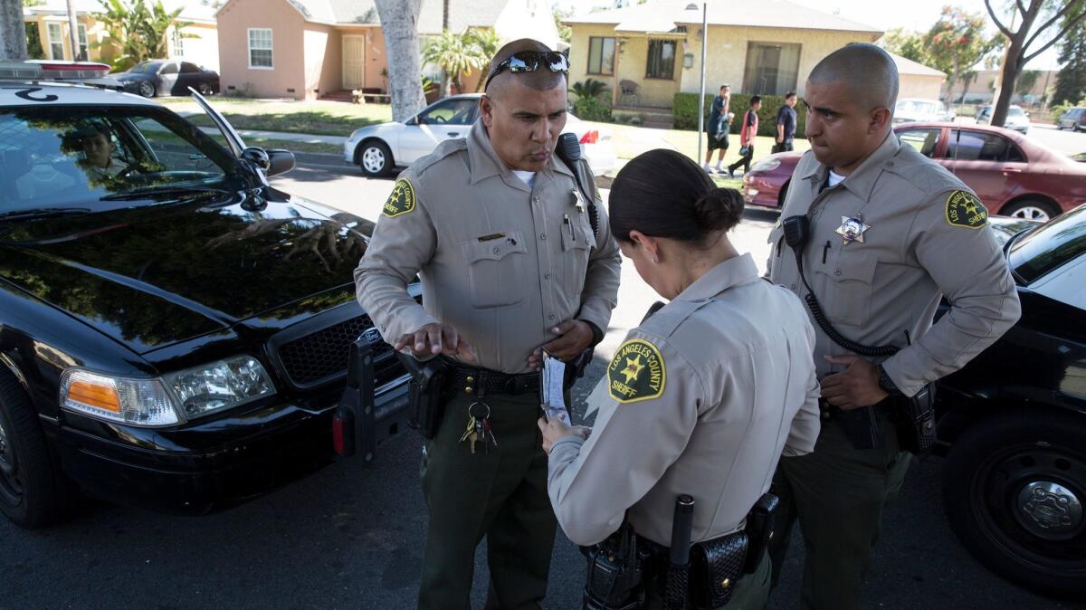 Sheriff's Deputy Marino Gonzalez, left, talks with colleagues while investigating a disturbance in June in Maywood. Senate Bill 54 would establish clear divisions between law enforcement and federal immigration authorities.