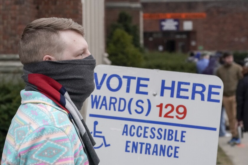 Voters masked against coronavirus line up to vote in Milwaukee.