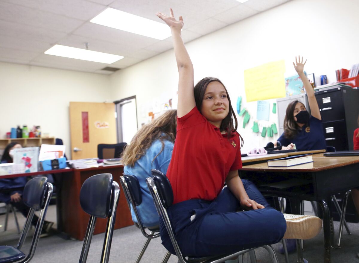 Lilianna Naizer-Baldwin,10, foreground center, raises her hand during her Spanish class at the New Mexico International School in Albuquerque, N.M., on Friday, May 27, 2022. Mary Baldwin a psychology intern at UNM Hospital Health science Center immigrated to the U.S. form Honduras when she was 10. Now her daughter Lilianna is the same age, and thanks to the dual language program she's fluent enough to cook banana-leaf-wrapped tamales with her Spanish-speaking grandmother. New Mexico is the only state in the country where the right to learn in Spanish is laid out the constitution. (AP Photo/Cedar Attanasio)