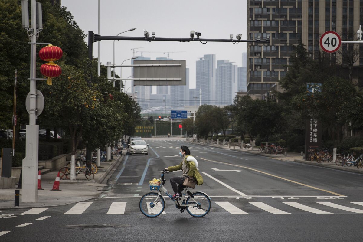 A woman rides a bicycle on an empty street in Wuhan, China.