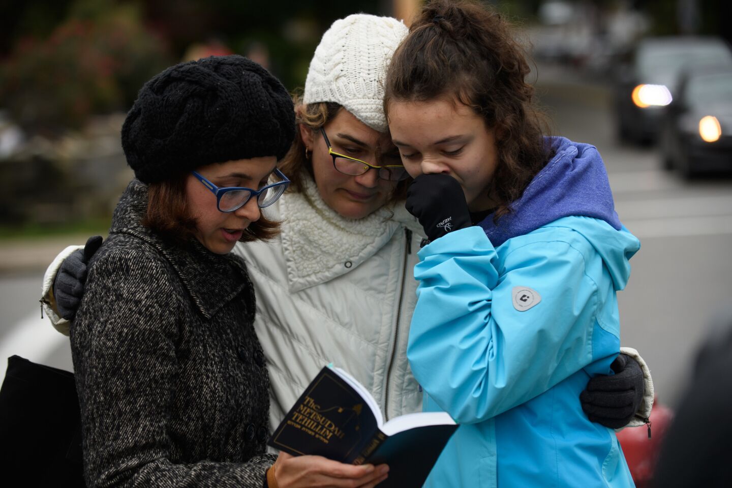 Tammy Hepps, Kate Rothstein and her daughter, Simone Rothstein, 16, pray from a prayerbook a block away from the site of a mass shooting at the Tree of Life synagogue in Pittsburgh on Oct. 27, 2018.