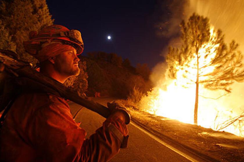 A firefighter watches a backfire burn off East Grade Road on Palomar Mountain after nightfall.