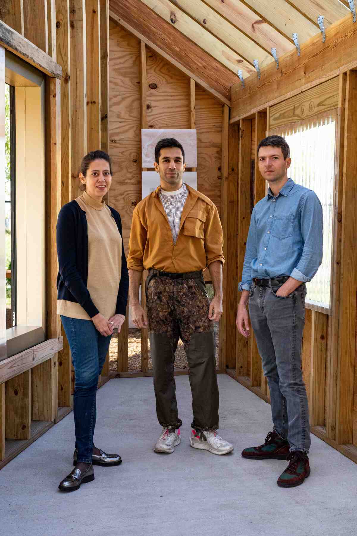 Three people stand inside a mock-up used for a building project.