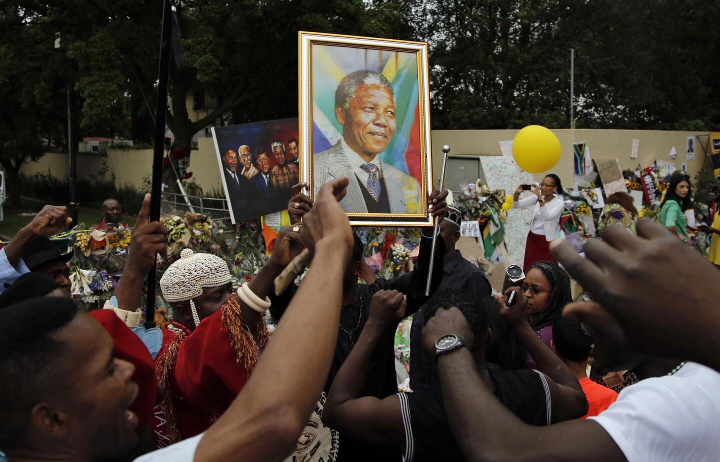 Mourners from Nigeria sing outside the home of former South African President Nelson Mandela in Johannesburg, South Africa. Scores of heads of state and government and other foreign dignitaries, including royalty, are beginning to converge on South Africa as the final preparations for Tuesday's national memorial service for Mandela are put in place.