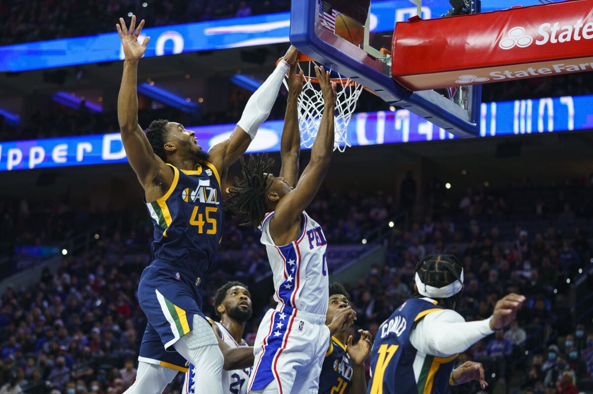 Philadelphia 76ers' Tyrese Maxey, center, goes up to shoot with Utah Jazz's Donovan Mitchell, left, defending during the first half of an NBA basketball game, Thursday, Dec. 9, 2021, in Philadelphia. (AP Photo/Chris Szagola)