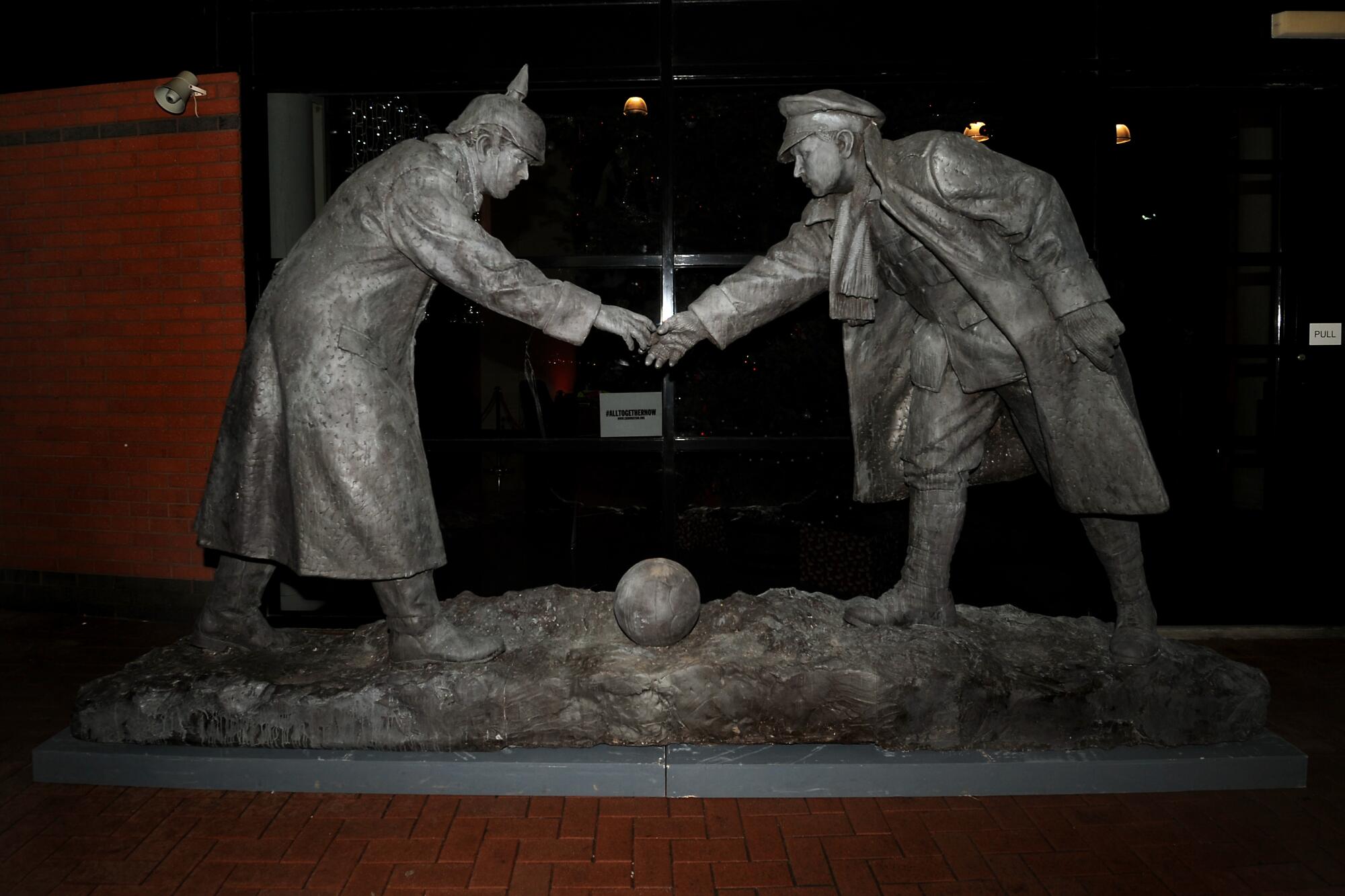 A World War I sculpture shows two soldiers, one British and the other German, greeting each other next to a soccer ball