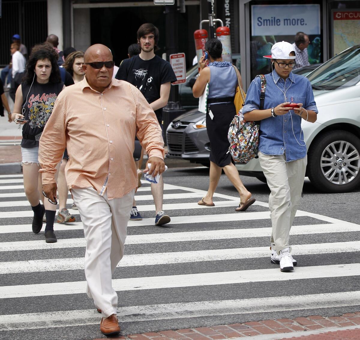 A pedestrian texts while crossing the street in downtown Washington.