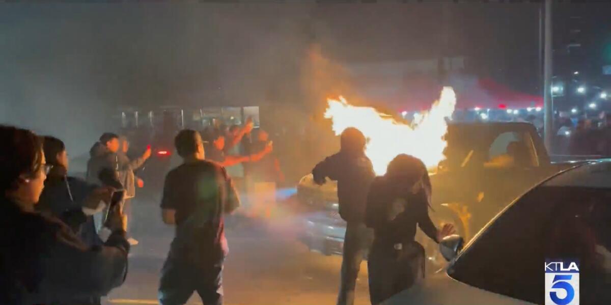An image from video shows people cheering in the street and a truck in flames.