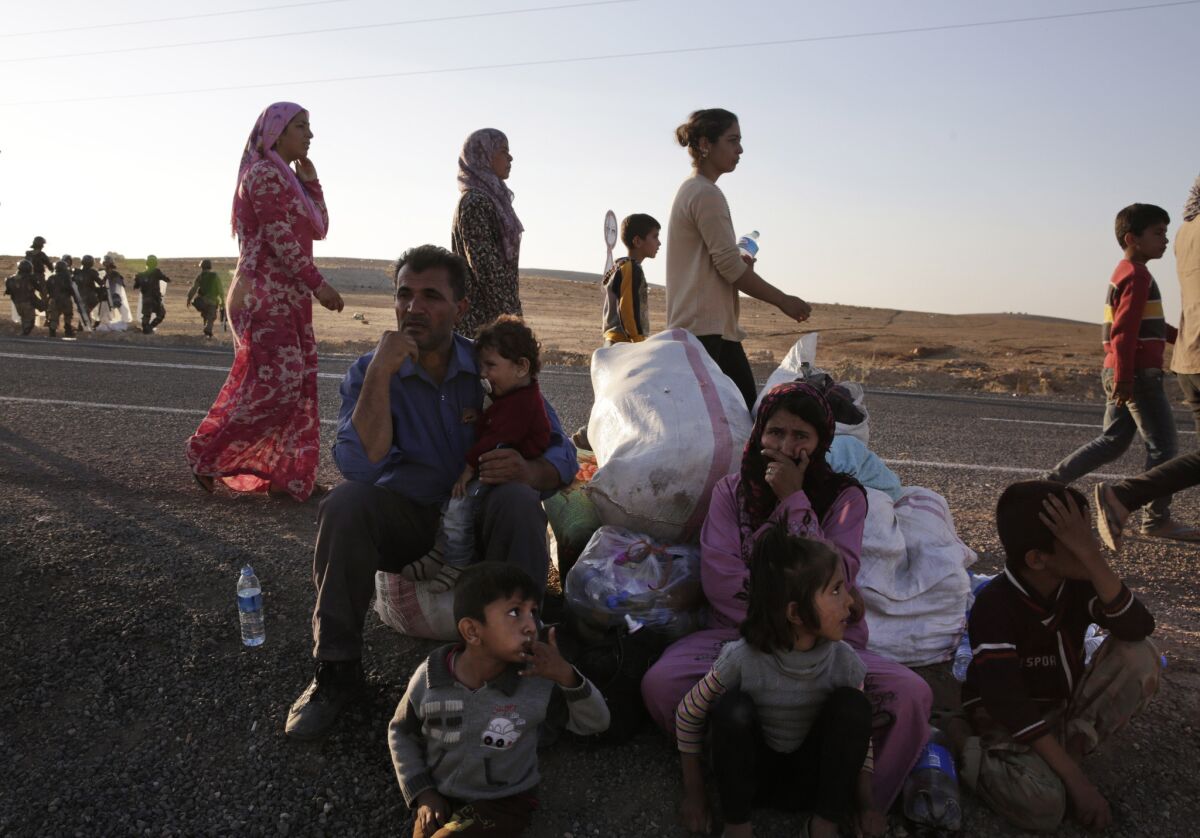 Kurdish refugees wait by the side of the road Oct. 5 near Suruc, Turkey, after their arrival from Kobani, Syria. Fighting between Syrian Kurds and the militants of Islamic State has intensified in Kobani.