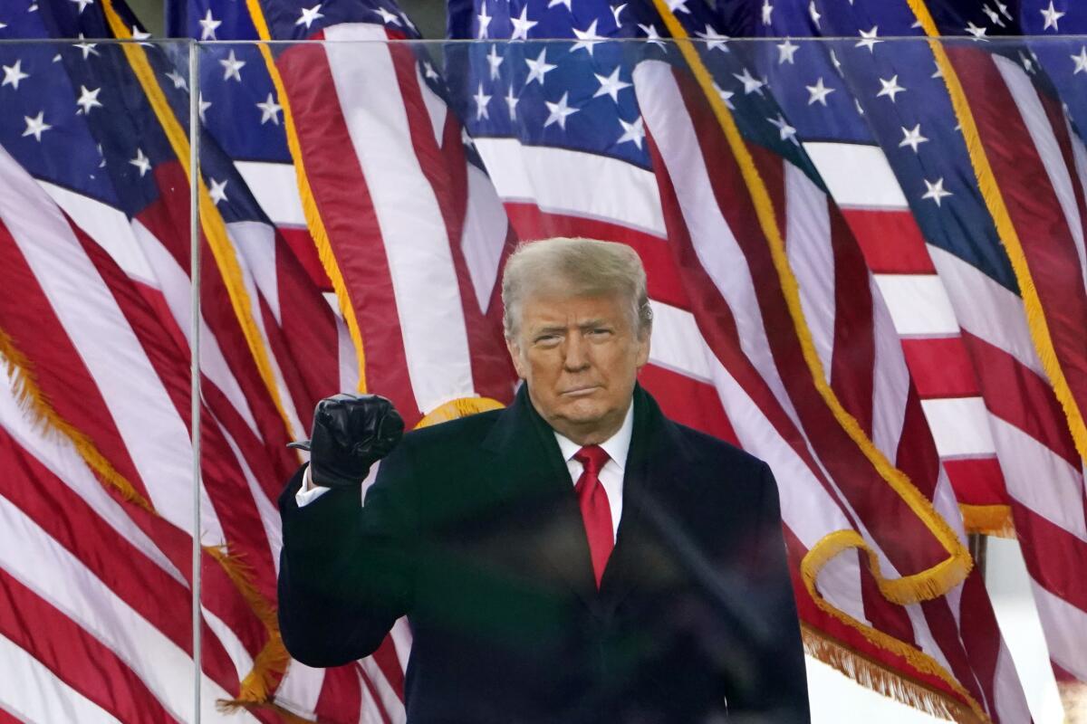 In a Jan. 6, 2021, file photo, then-President Trump holds up a fist at a rally in front of U.S. flags.