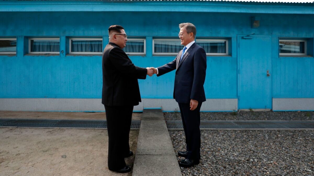 North Korea's leader Kim Jong Un, left, shakes hands with South Korea's President Moon Jae-in at the Military Demarcation Line that divides their countries ahead of their summit at the truce village of Panmunjom.