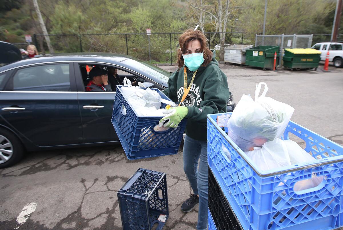 Volunteer Chris Etow loads containers filled with bags of groceries for a visitor outside the Laguna Food Pantry on Wednesday.