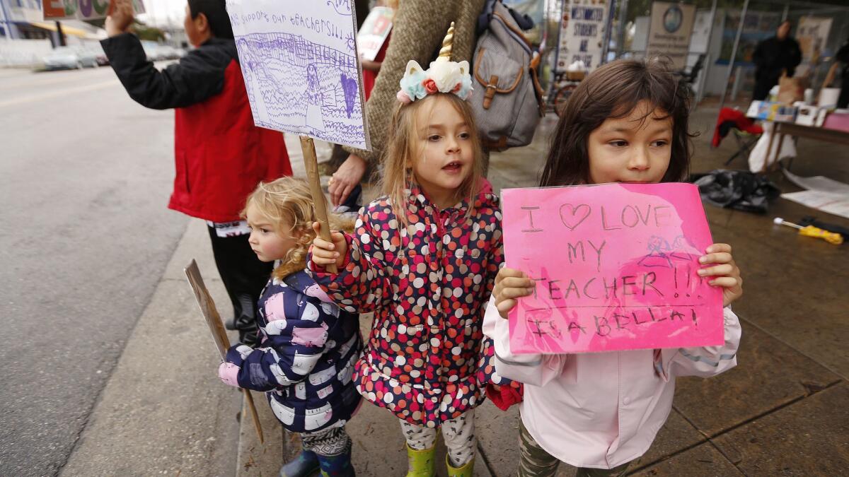 Kindergarten students Isabella Dam, right, and Ava Berg, middle, joined with sister Silke Berg, left, holding signs to support their teacher outside Westminster Elementary School in Venice.