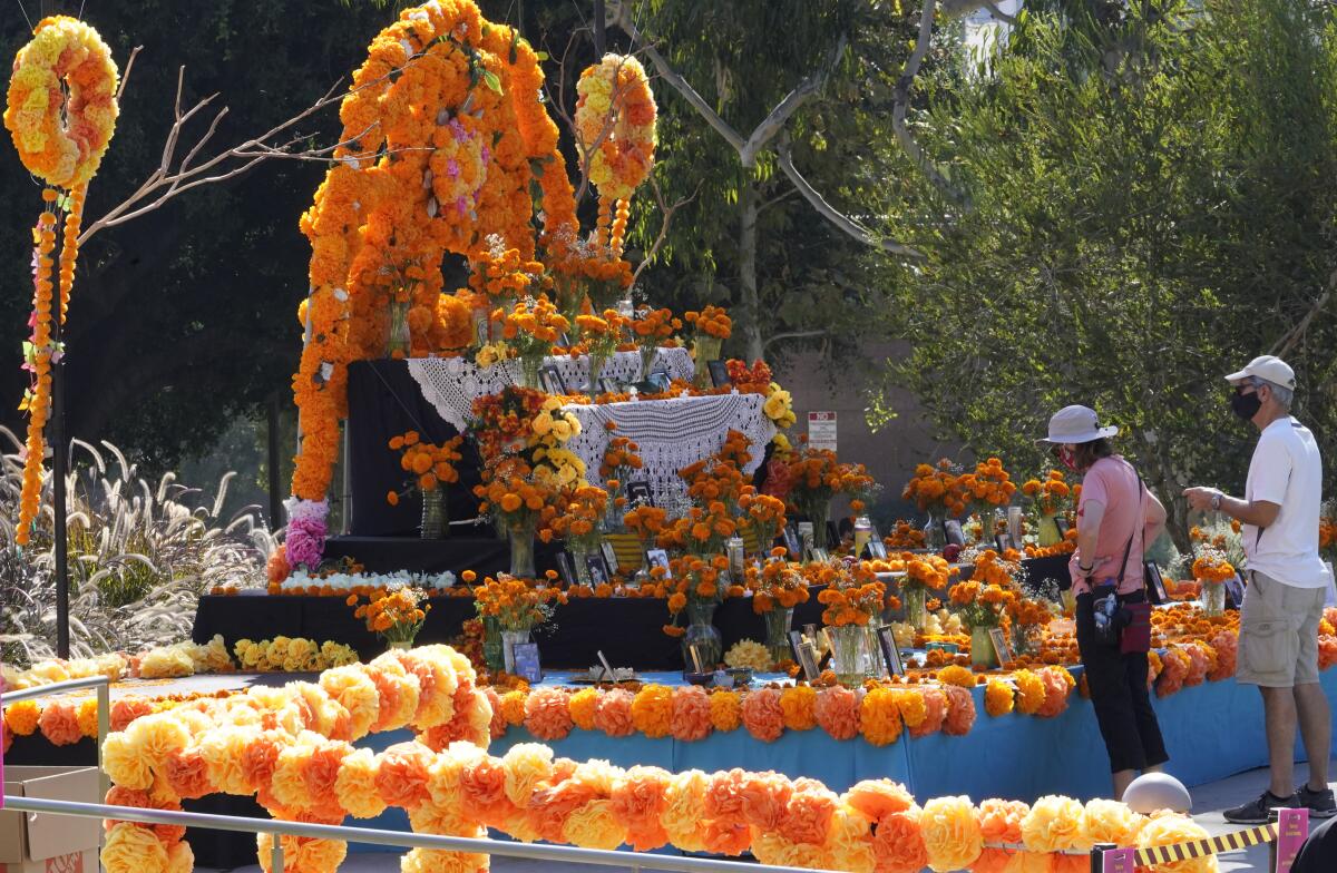 Unas personas observan una ofrenda colocada por la festividad del Día de los Muertos en Los Ángeles