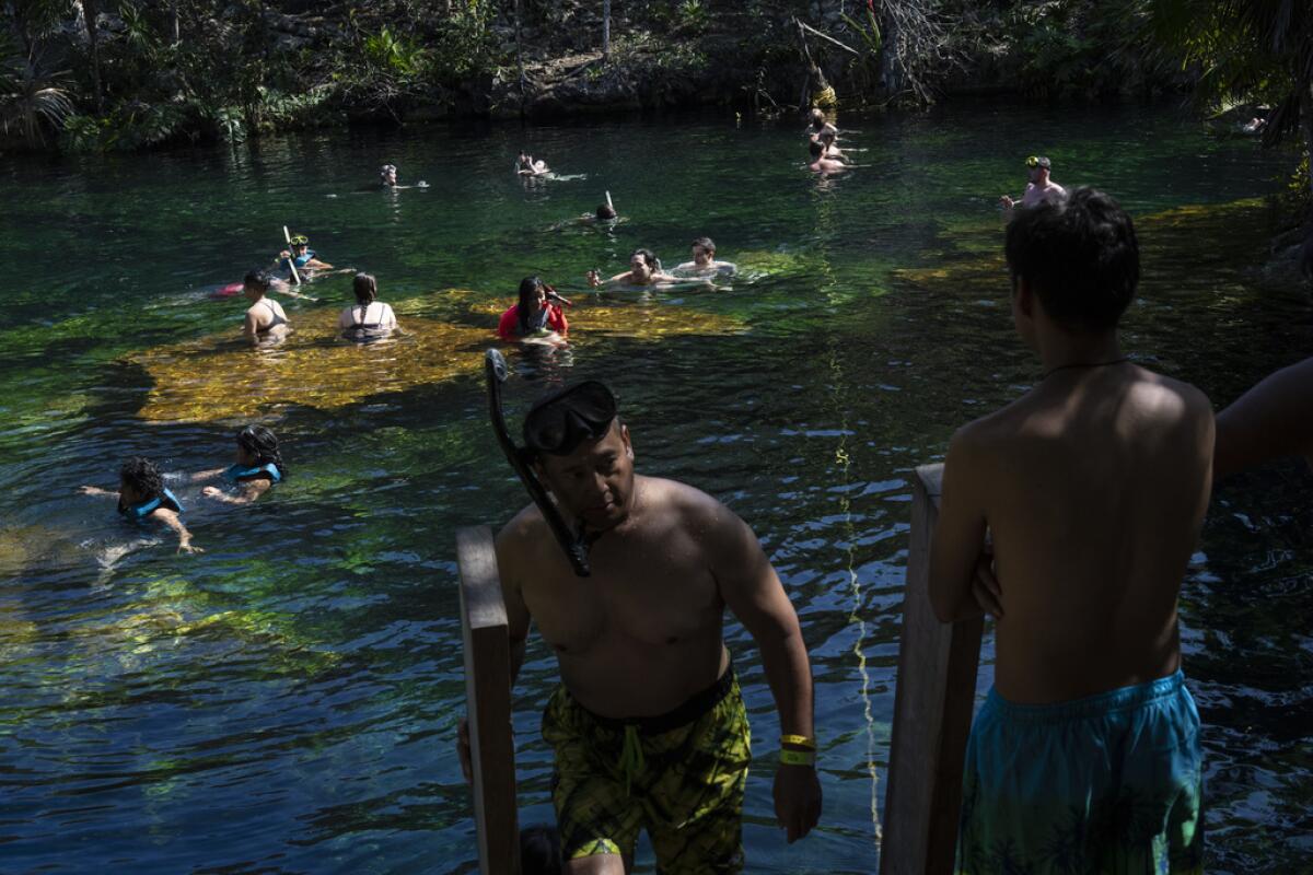 Turistas nadan en las aguas del cenote "Jardín del Edén