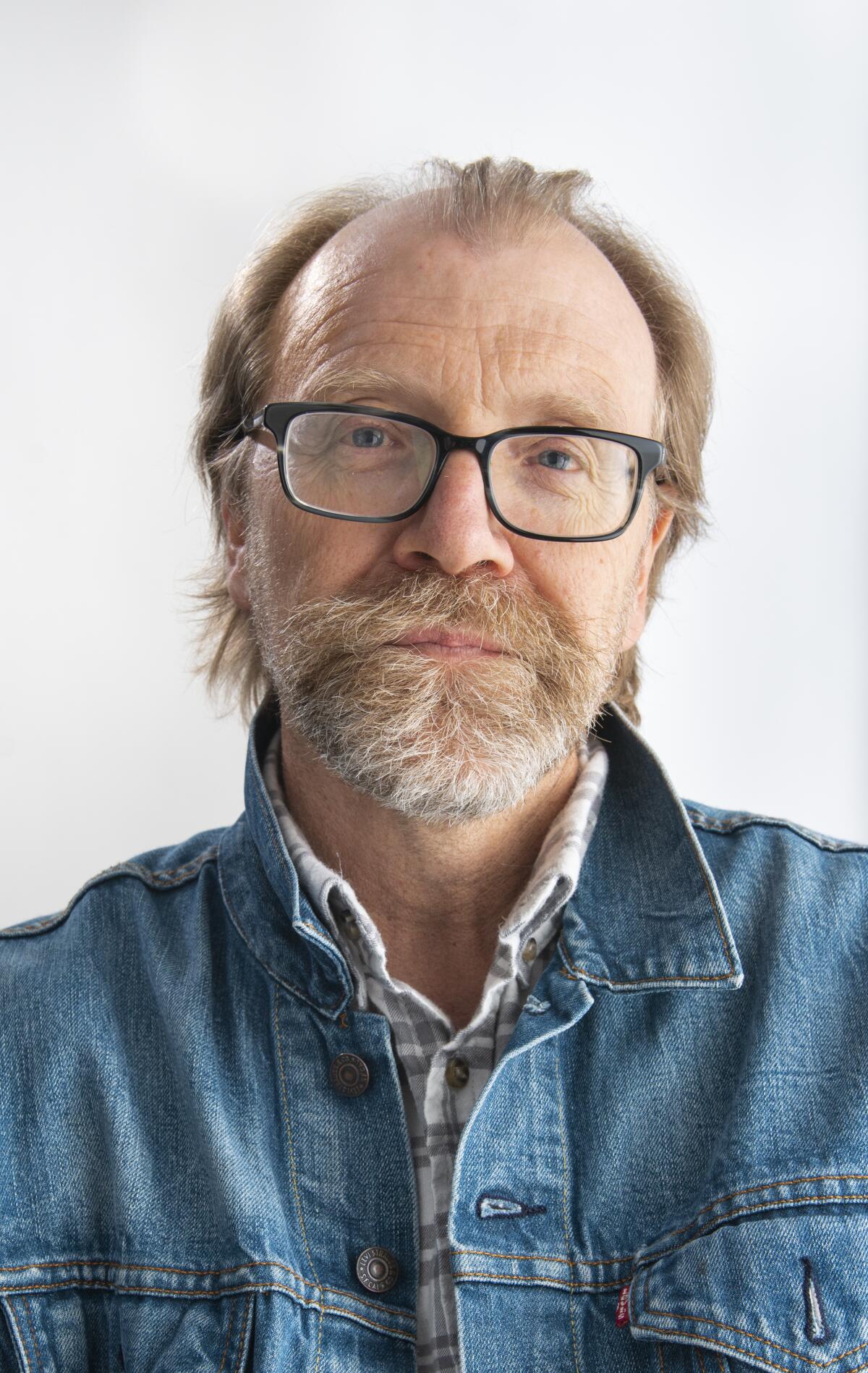 A man in glasses and a denim jacket