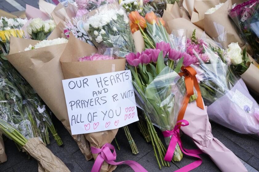 Una nota se junto a ofrendas florales cerca de la escena de un crimen en Bondi Junction, Sydney, el domingo 14 de abril de 2024. después de que varias personas fueran apuñaladas en un centro comercial el día anterior. La nota dice "Nuestros corazones y oraciones están con todos vosotros". (AP Foto/Rick Rycroft)