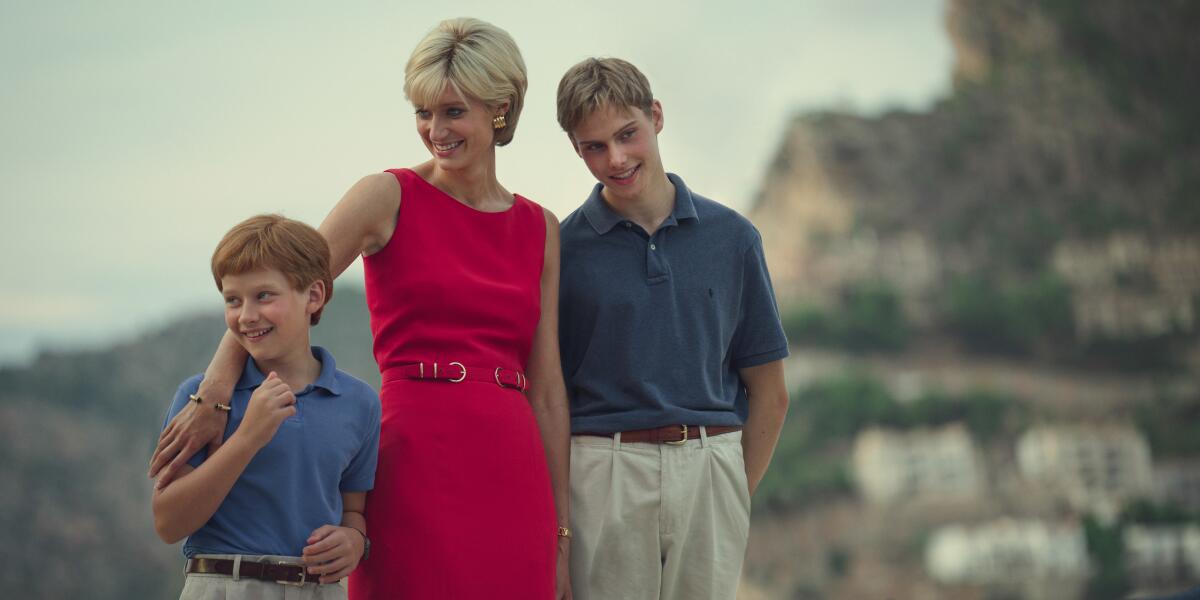 In a scene from "The Crown, Prince Harry and Prince William in blue polos and khakis, stand next to Diana in a red dress.