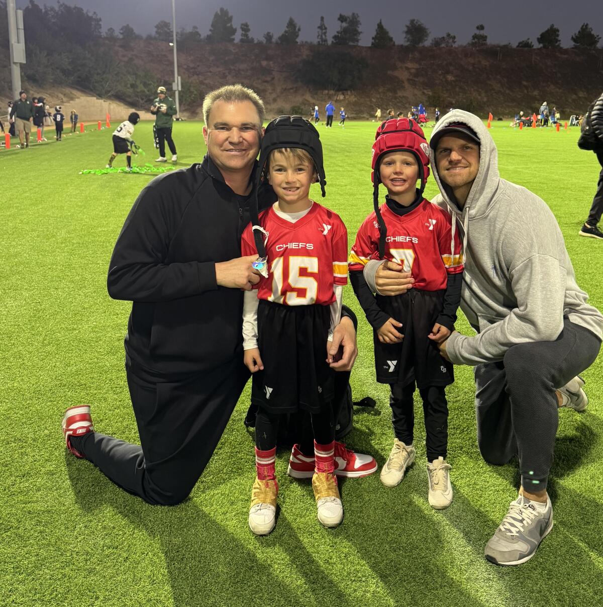 Casey Clausen, left, and Jimmy Clausen, right, pose for a photo with their sons.