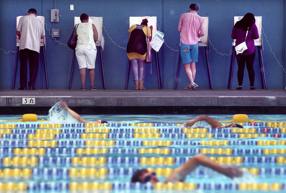 Voters cast their ballots as others swim laps at a pool in Echo Park on Tuesday.