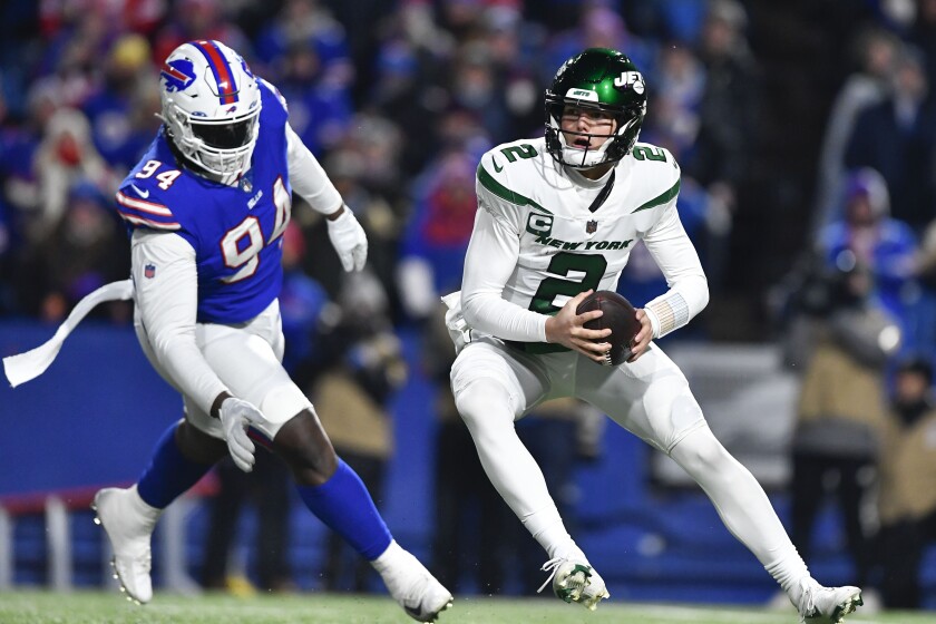 New York Jets quarterback Zach Wilson, right, looks to throw under pressure from Buffalo Bills' Vernon Butler during the first half of an NFL football game, Sunday, Jan. 9, 2022, in Orchard Park, N.Y. (AP Photo/Adrian Kraus)