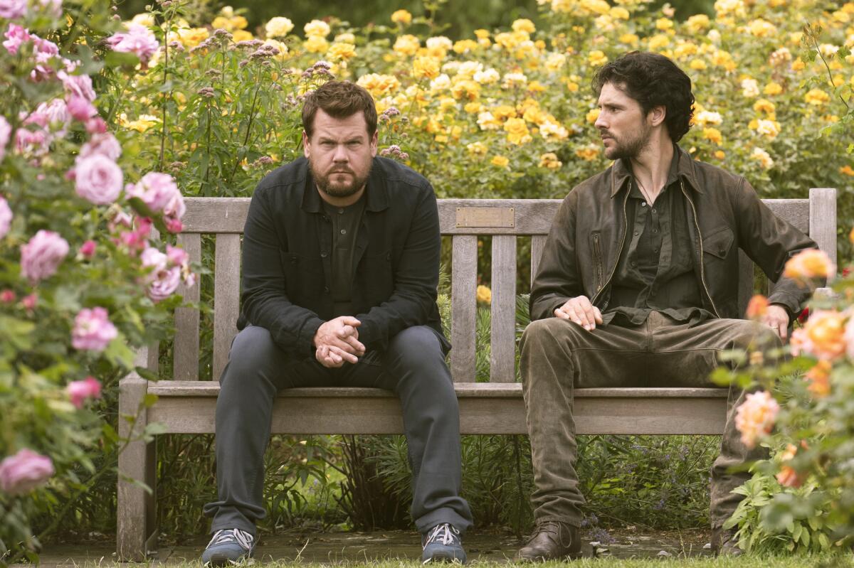 Two men sitting on a bench in a flower garden