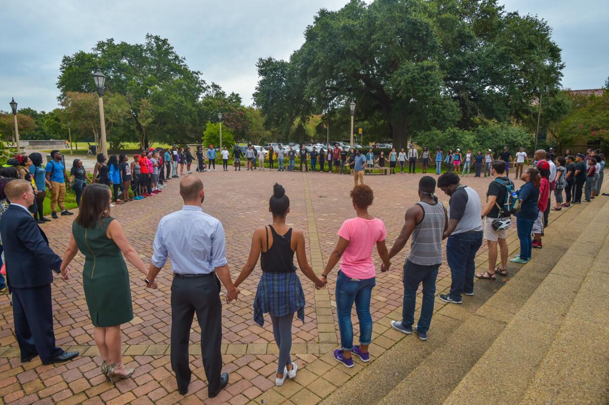 Gente rezando durante una vigilia organizada por Myron Smothers en el Memorial Tower, en el campus de la Universidad Estatal de Louisiana, en Baton Rouge, Louisiana, el lunes 11 de julio de 2016. (Scott Clause/The Daily Advertiser via AP)