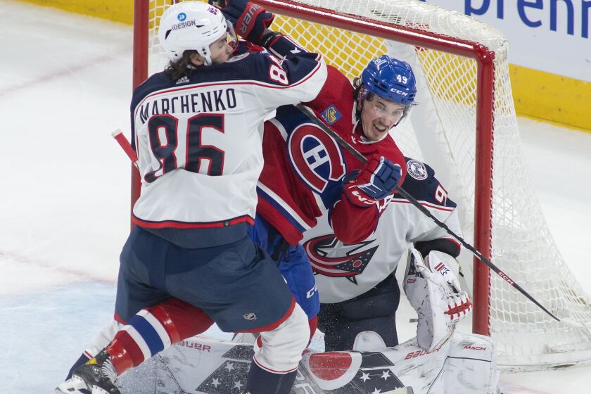 Columbus Blue Jackets right wing Kirill Marchenko (86) tries to remove Montreal Canadiens left wing Rafael Harvey-Pinard (49) from in front of Blue Jackets goaltender Elvis Merzlikins (90) during second-period NHL hockey game action in Montreal, Saturday, March 25, 2023. (Peter McCabe/The Canadian Press via AP)