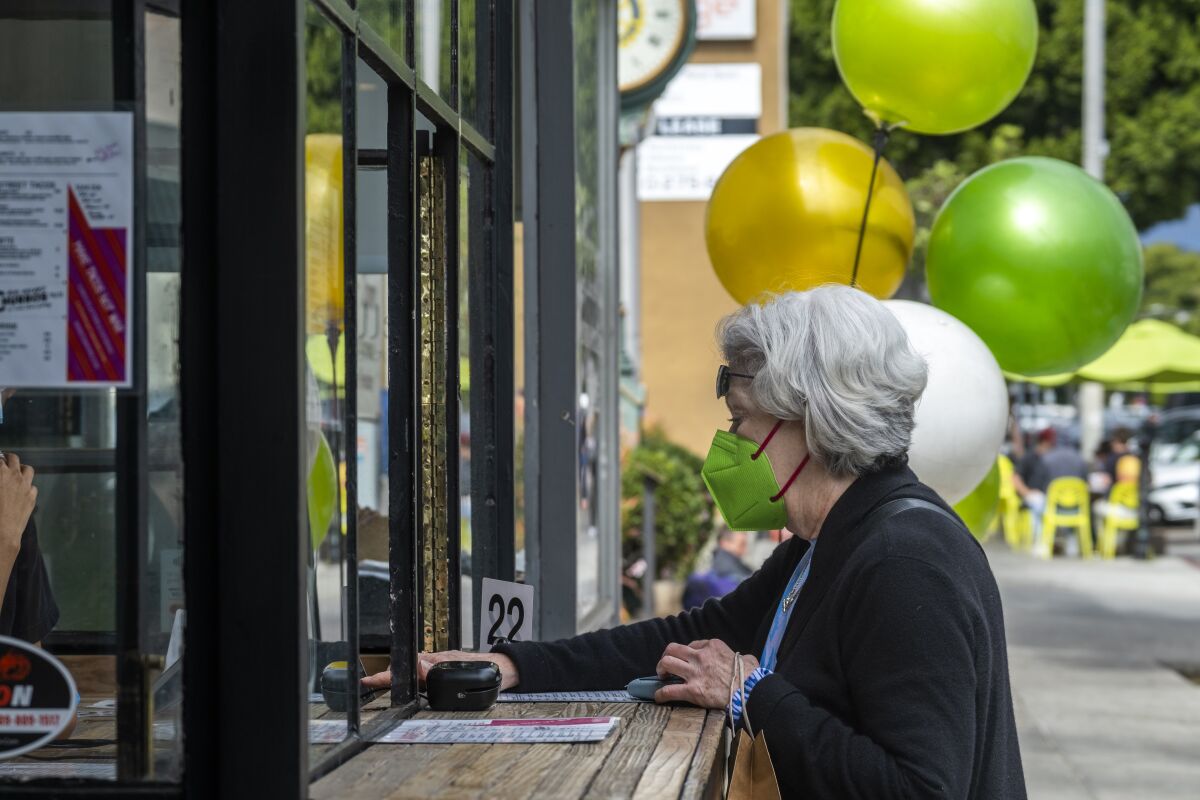 A masked woman stands at a counter.