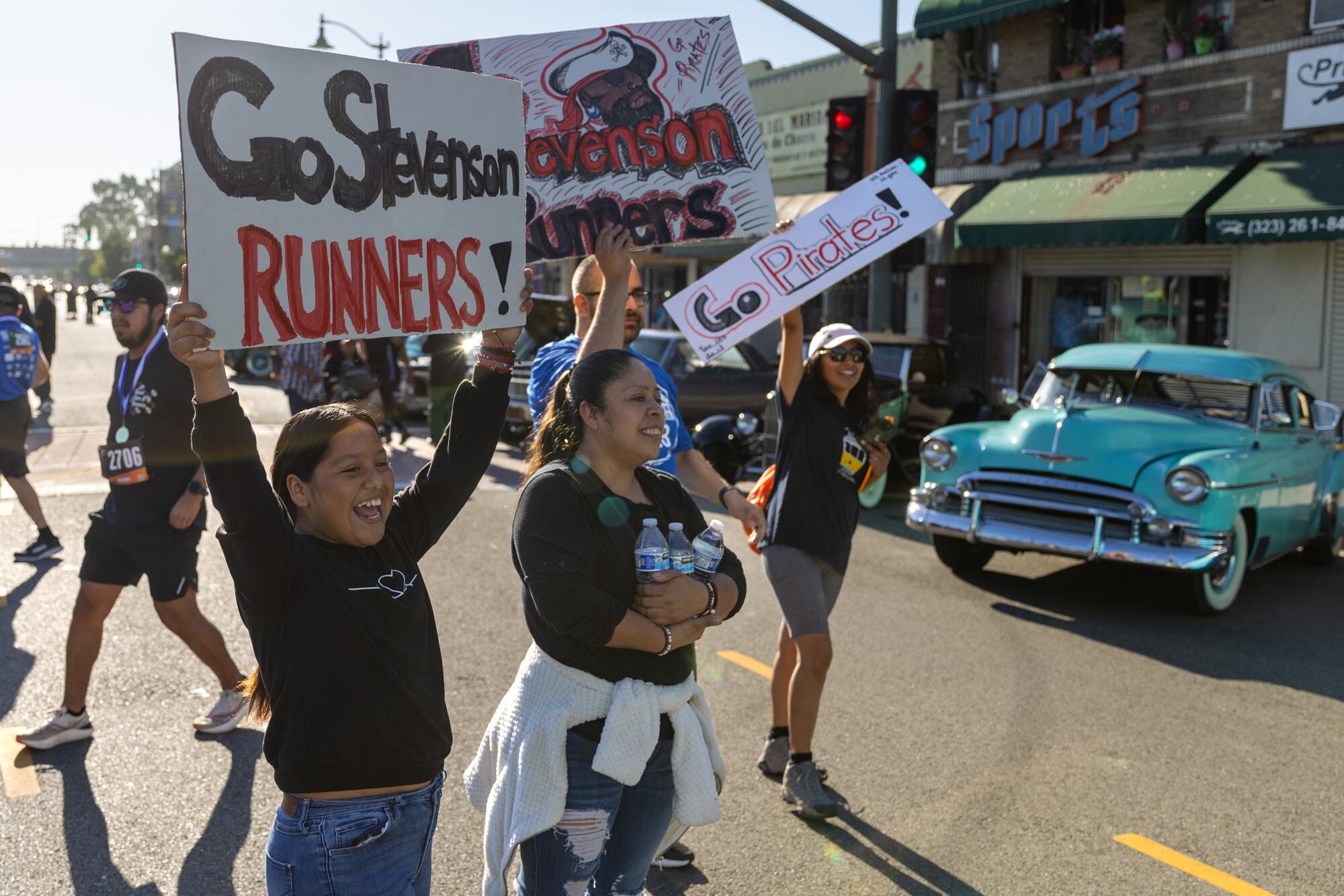 People hold signs waiting for runners to cross finish line of the Boyle Heights 5K