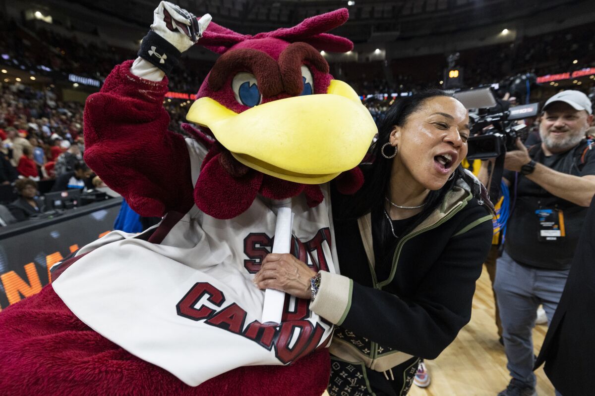 South Carolina head coach Dawn Staley celebrates with the South Carolina mascot "Cocky" after defeating Maryland in an Elite 8 college basketball game of the NCAA Tournament in Greenville, S.C., Monday, March 27, 2023. (AP Photo/Mic Smith)