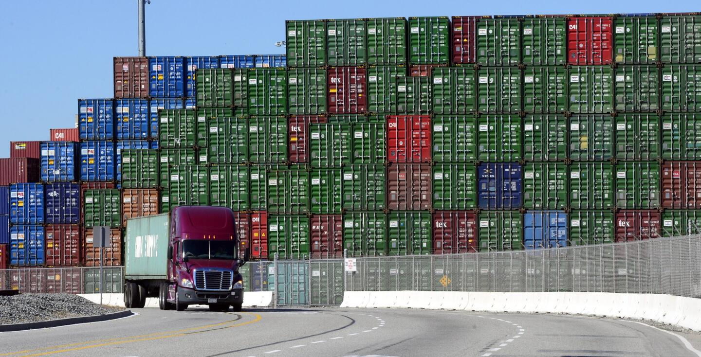 A truck passes by containers as cargo ships sit idle in the ports of Los Angeles and Long Beach on Feb. 12.