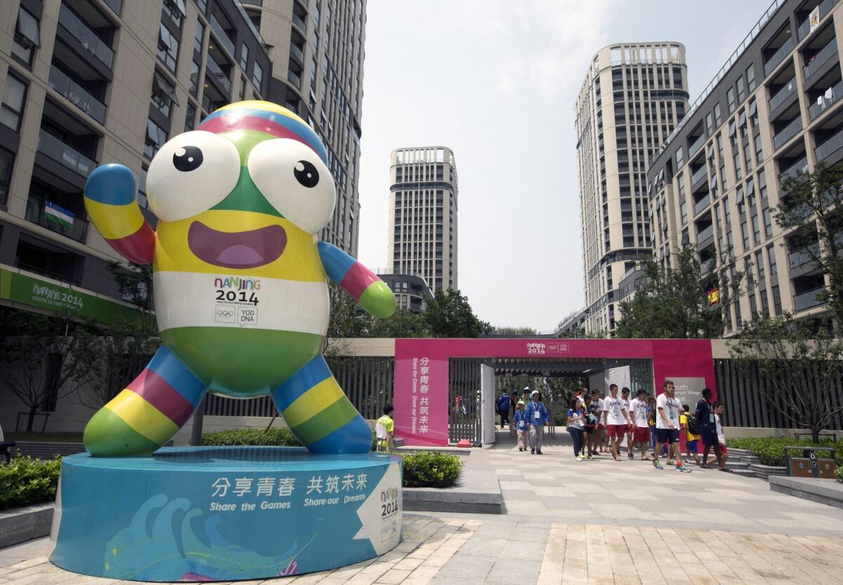 An installation of "Nanjing Lele" is displayed as athletes and staff come out of the Youth Olympic Village in Nanjing, China, on Friday.