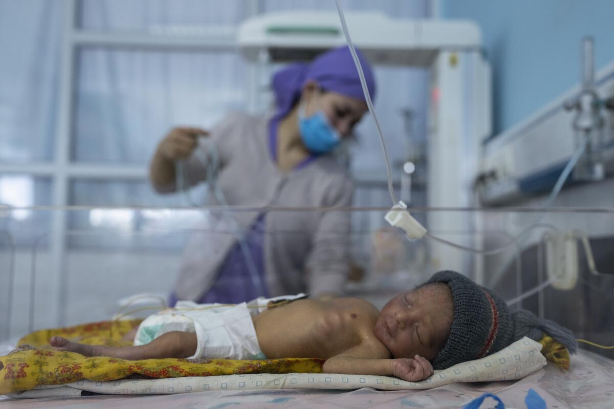 A nurse takes care of a baby in a neonatal intensive care unit 