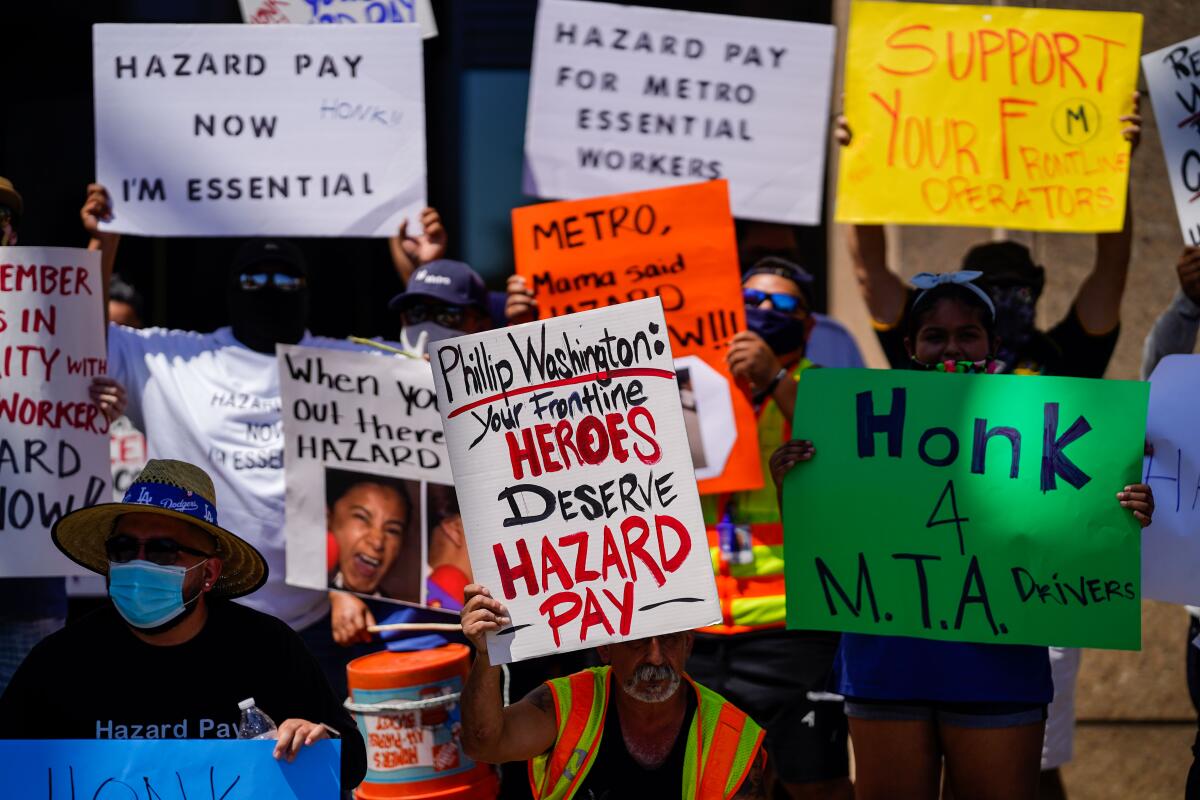 Bus operators hold up signs and protest outside Metro headquarters in downtown Los Angeles for coronavirus hazard pay