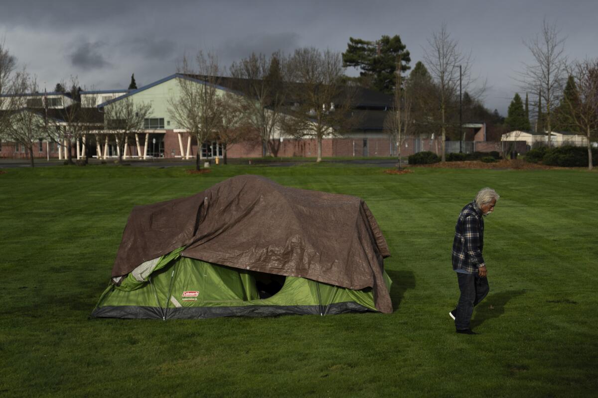 A homeless person walks near a tent in Fruitdale Park in March in Grants Pass, Ore. 