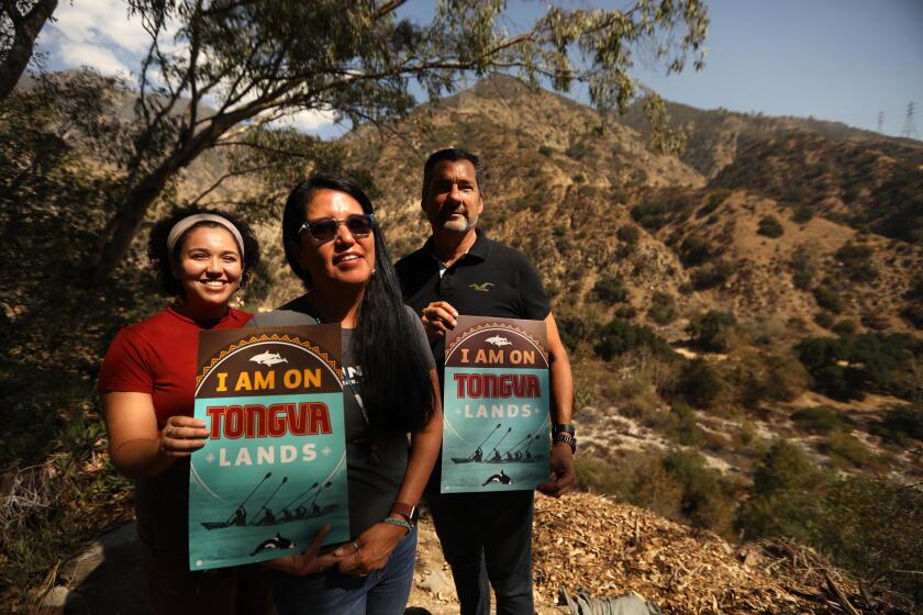 ALTADENA, CA - OCTOBER 7, 2022 - - Samantha Johnson, left, Tony Lassos, right, both with Tonga Taraxat Paxaavxa Conservancy and Kimberly Morales Johnson, with the Gabrieleno/Tongva San Gabriel Band of Mission Indians and vice president of the Tongva Taraxat Paxaavxa Conservancy, stand on the land, near Eaton Canyon, that was transferred in March to the Tongva community in Altadena on October is 7 2022. The Tongva Taraxat Paxaavxa Conservancy set up a nonprofit to receive the land, the first "land back" opportunity for the Tongva people. The Tongva community plans to use the land to perform ceremony, practice rituals and customs, educate themselves and guests of Tongva culture, provide housing assistance, and grow indigenous plants. The land is believed to be an old gathering space for summer harvesting and religious practices, given its location in Eaton Canyon and at the foot of the San Gabriel Mountains and an old fire ring that predated the land's owners. (Genaro Molina / Los Angeles Times)